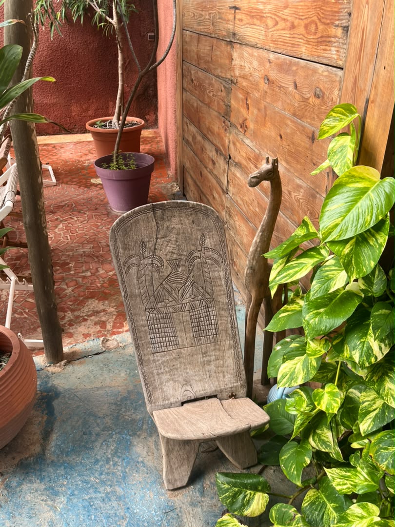 Siège en bois gravé près d’une haute forme animale sculptée et de plantes vertes