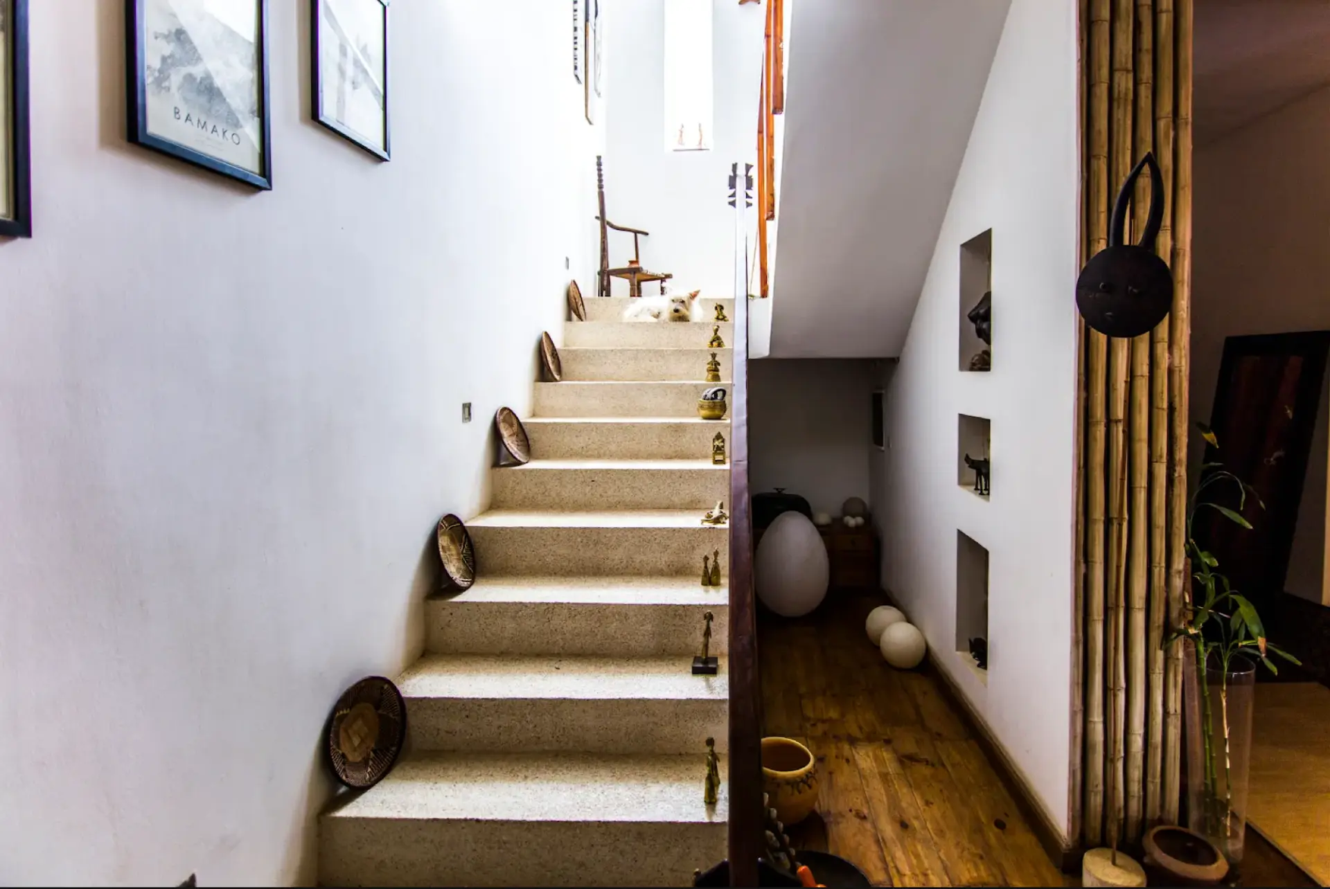 Bright interior staircase lined with Senegalese sculptures and pottery