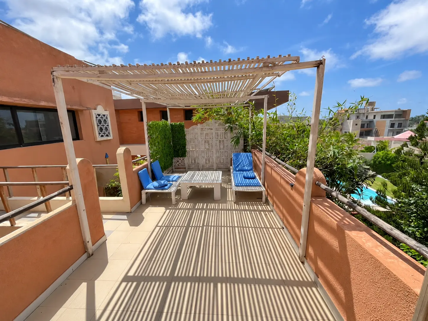 Blue-cushioned seating beneath the wooden pergola
