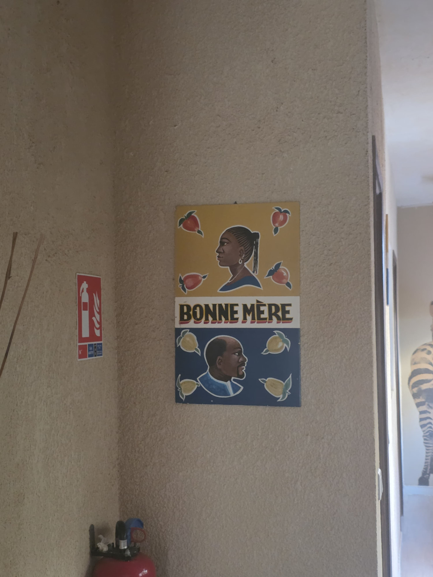 Enseigne peinte avec deux portraits de profil, des motifs de fruits et les mots Bonne Mère sur un mur texturé