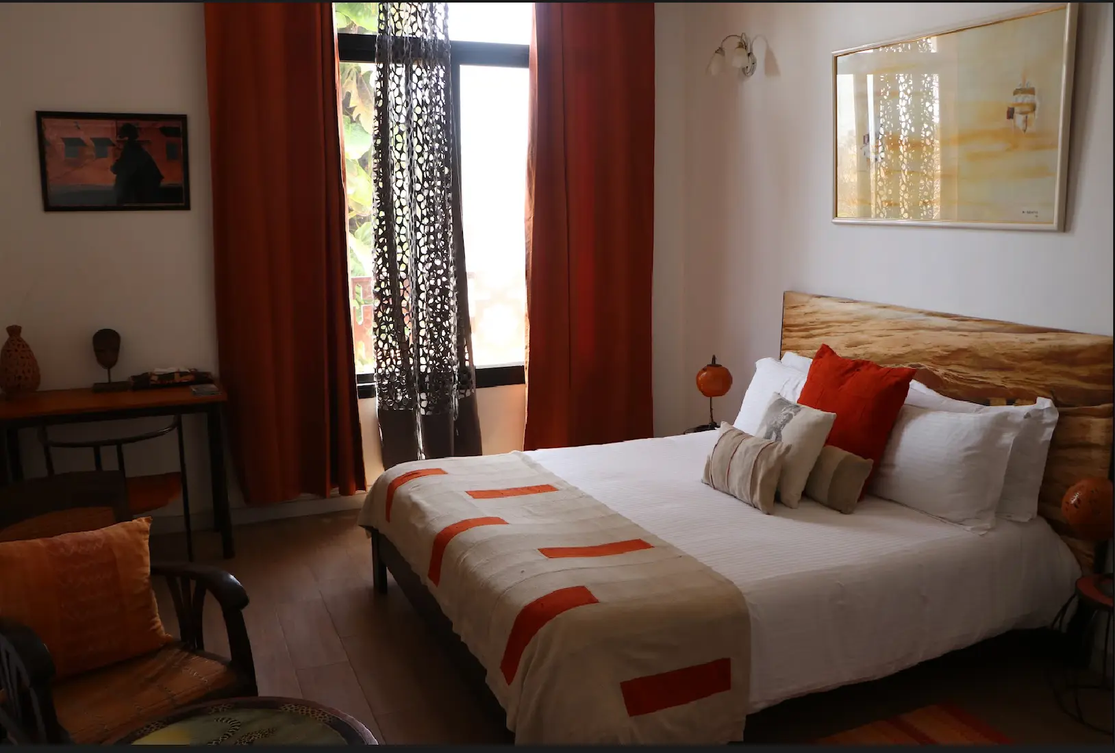 Guest bedroom with wooden headboard, white linen and mudcloth throw