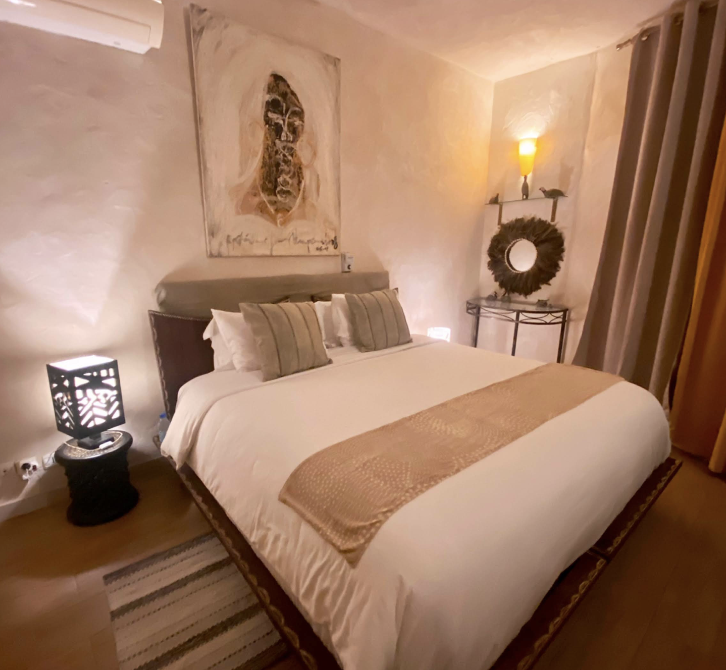 Pintades room — elegant king bed with African mask artwork and soft lighting