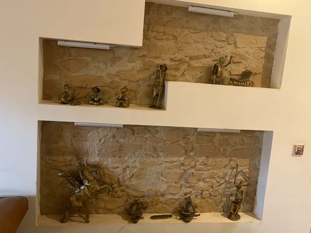 Niches murales décalées à fond de pierre présentant une collection de petites figures en métal