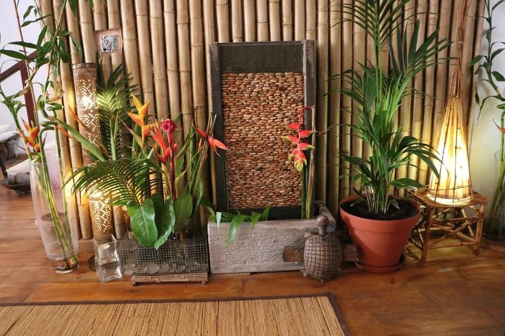 Textured artwork between potted palms beside a bamboo screen