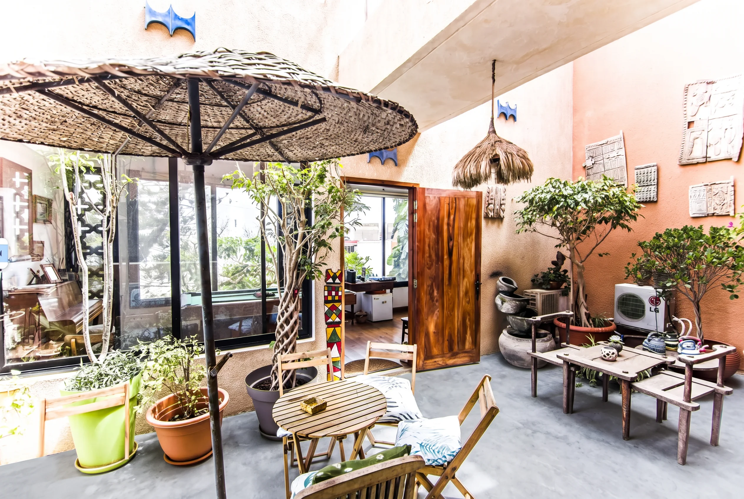 Upstairs terrace with woven parasol, plants and carved wall panels