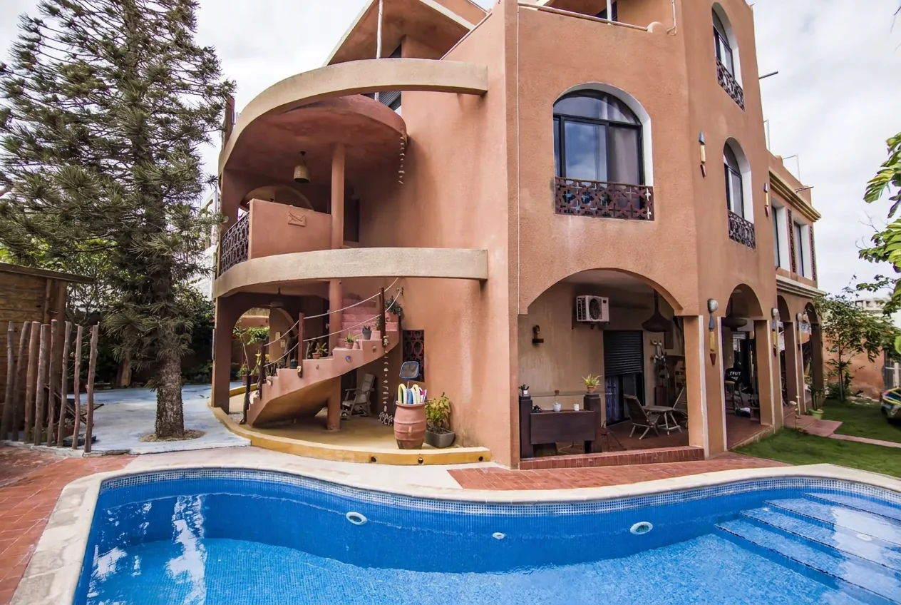 Terracotta facade of Maison Sahel with curved balconies and swimming pool
