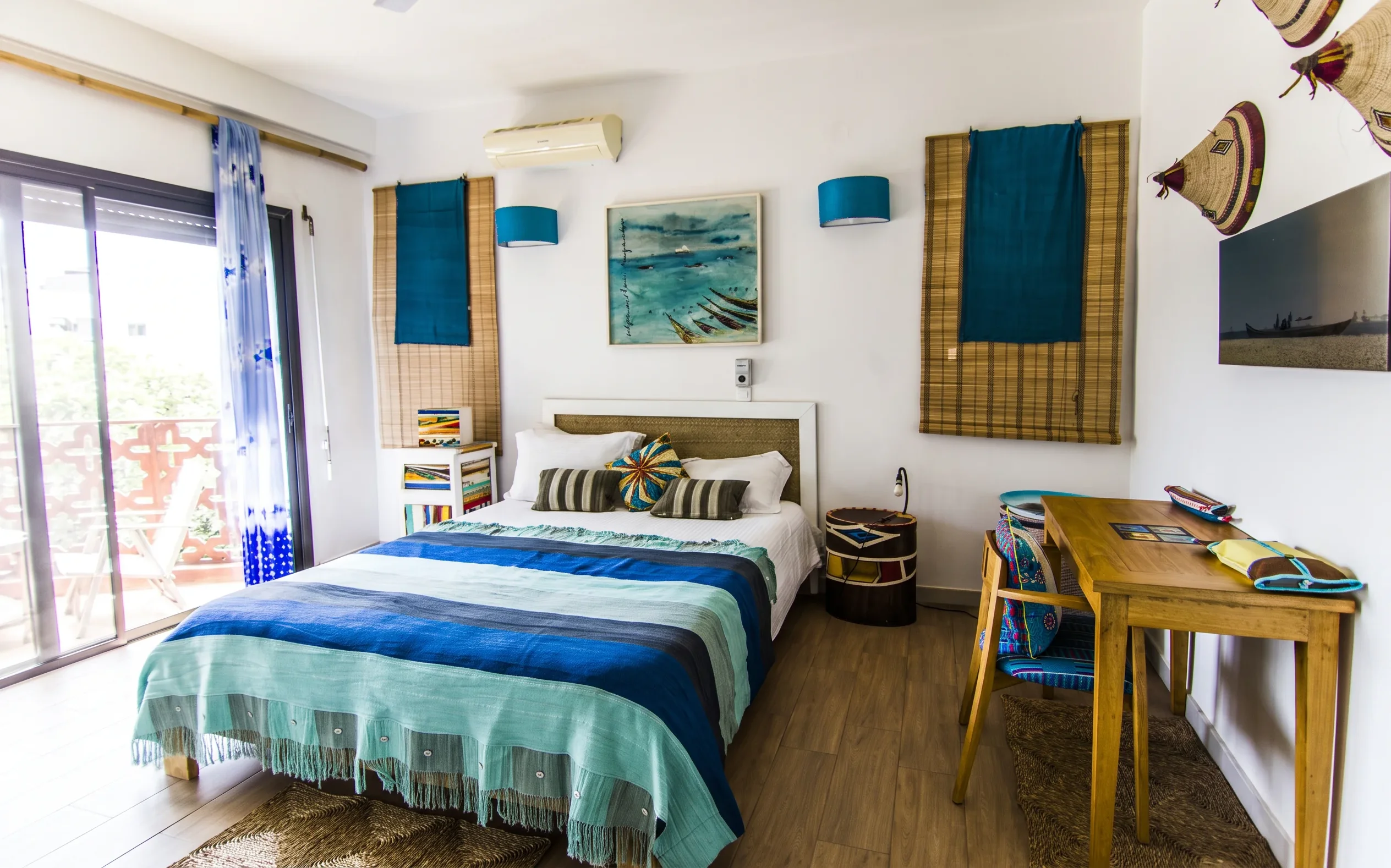 Pirogue room — king bed with indigo and teal Sahel textiles, balcony access