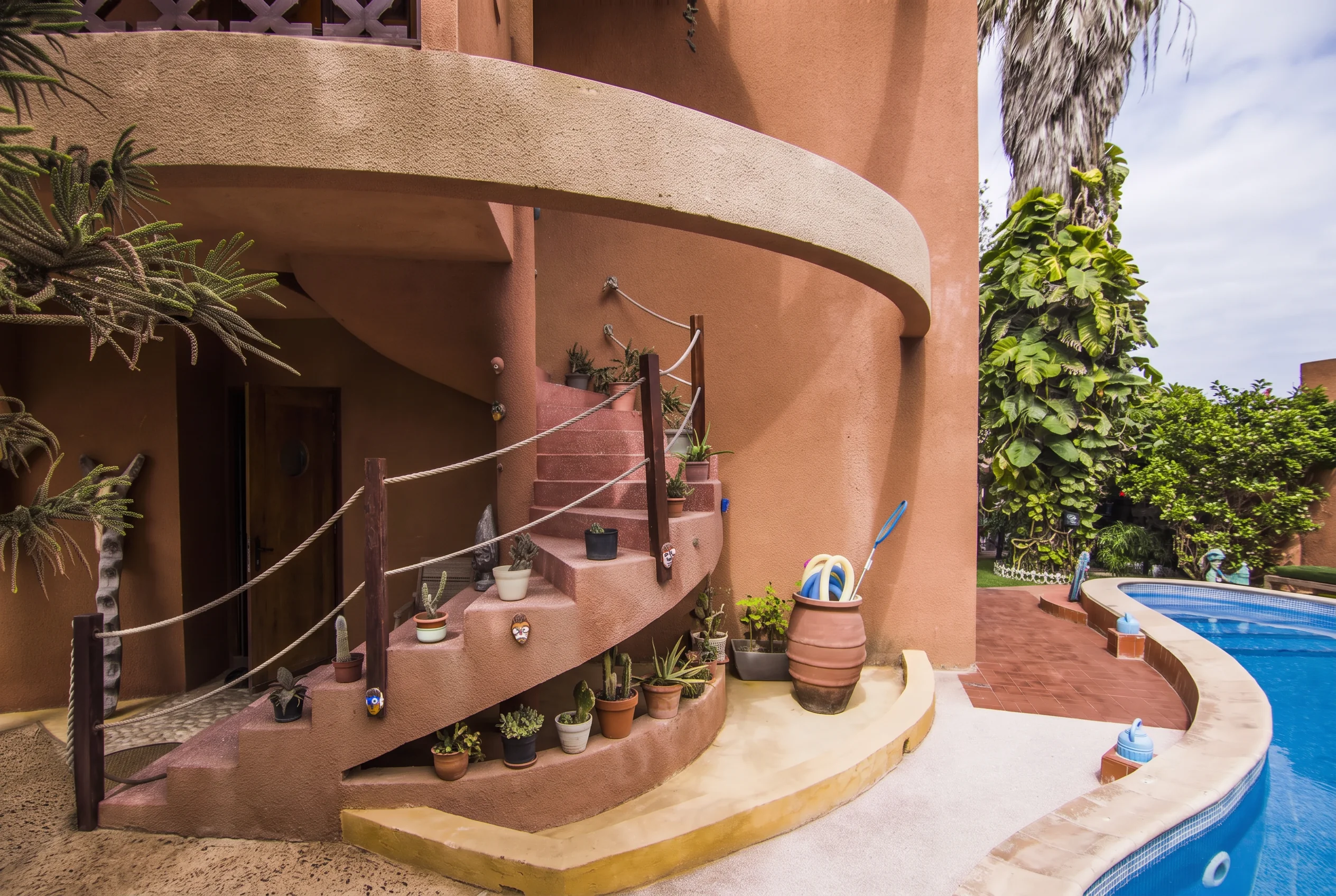 Curved terracotta staircase beside the swimming pool at Maison Sahel